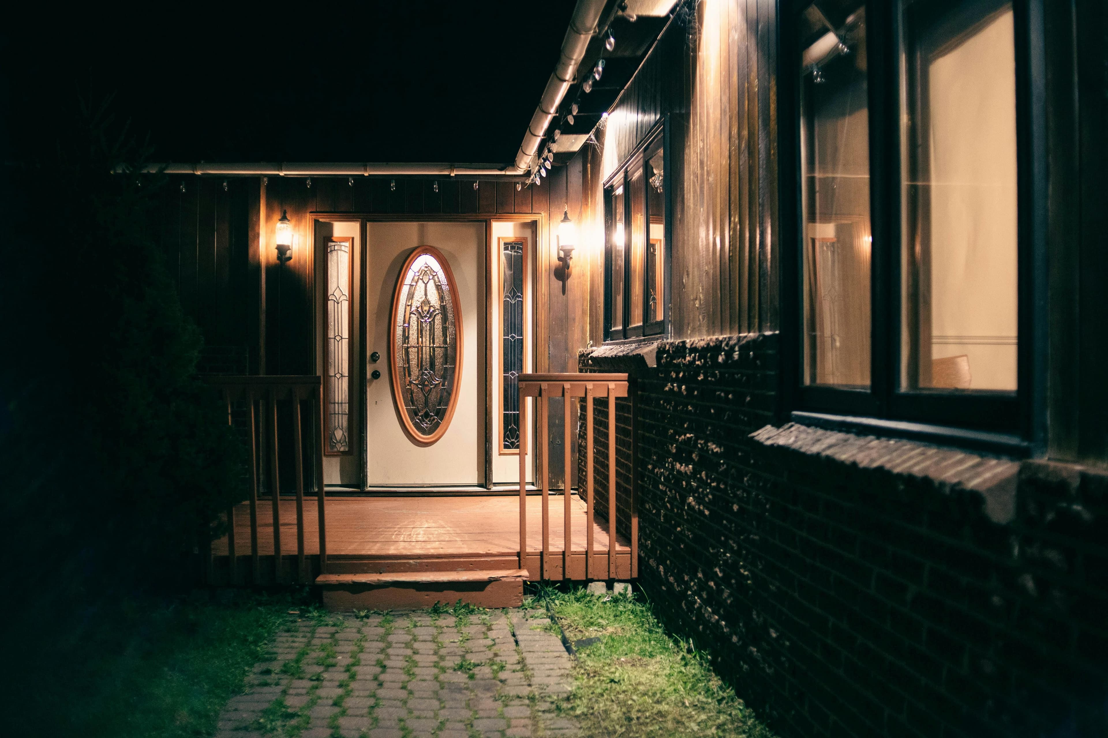 A warmly lit house entrance with decorative glass doors and glowing lantern lights at night.